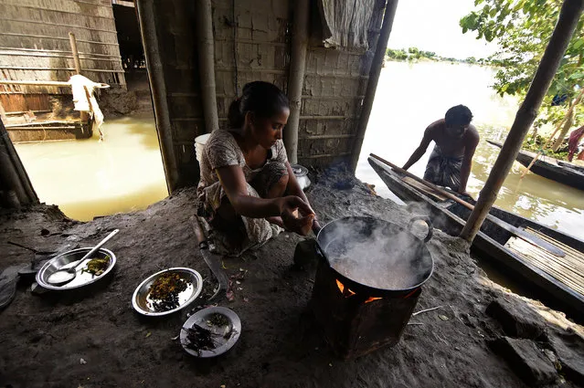 A woman cooks inside her partially submerged house at a village in Morigaon district in Assam, August 20, 2017. (Photo by Anuwar Hazarika/Reuters)