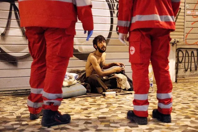 A homeless person talks to Red Cross workers in Rome, Italy, March 17, 2020. Since the coronavirus crisis, Red Cross workers have been increasing their daily activities to meet the growing needs of the homeless in Rome. With nobody around on the streets to give them food or money, and restaurants that would usually donate leftovers closed, homeless are struggling to find food and other supplies to keep them going. (Photo by Guglielmo Mangiapane/Reuters)