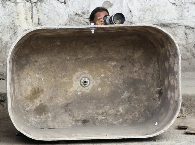 A photographer takes his position behind an empty water tank during an operation at Alemao slum in Rio de Janeiro November 27, 2010. (Photo by Sergio Moraes/Reuters)