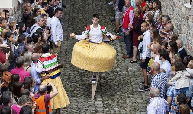 A resident, wearing a traditional costume and walking on stilts, takes part in a “colorful dance” along a slope as part of a festival called “The Anguiano Dancers” in Anguiano, La Rioja, northern Spain, 22 July 2016. A total of eight dancers walked down the street slope turning like human spinning tops on 45-cm-high stilts to worship the town's patron, Mary Magdalene, in a tradition that dates back to 1603. (Photo by Raquel Manzanares/EPA)