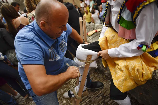 An assistant helps a dancer to prepare for taking part in stilts performance in honor of Saint Mary Magdalene in a street for the traditional “Danza de Los Zancos” (Los Zancos Dance), in the small town of Anguiano, northern Spain, Saturday, July 23, 2016. (Photo by Alvaro Barrientos/AP Photo)