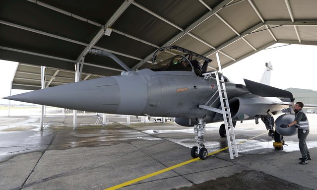 French soldiers and pilots work on a Rafale jet fighter at the air base in Mont de Marsan, southwestern France, August 31, 2015. For decades a symbol of fruitless endeavours to sell French fighter jets abroad, the Mont-de-Marsan pilot training centre in southwestern France opened its doors this summer to a large contingent of will-be Rafale pilots from Egypt – testimony to a long-awaited commercial breakthrough in which big sales contracts have been signed with Cairo. (Photo by Regis Duvignau/Reuters)