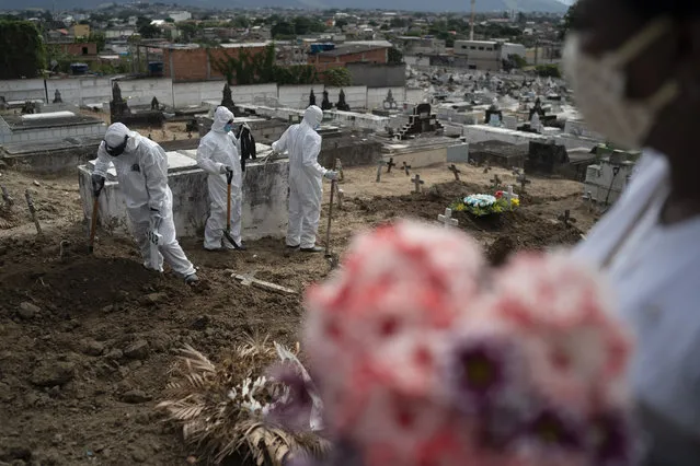 Cemetery workers wearing hazmat suits complete the burial of Ana Maria, a 56-year-old nursing assistant who died from the new coronavirus, in Rio de Janeiro, Brazil, Tuesday, April 28, 2020. Ana Maria's daughter Taina dos Santos said that the situation in the Salgado Filho public hospital where her mother worked is complicated and that some health workers have to buy their own protective gear. “She gave everything to her job until the very end”, said the 27-year-old daughter. (Photo by Leo Correa/AP Photo)