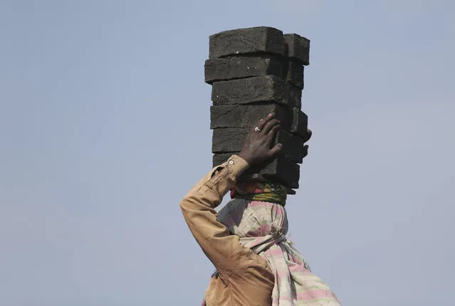 An Indian woman carries bricks as she works at a brick kiln on the outskirts of Hyderabad, India, Thursday, April 30, 2020. India says it has achieved tremendous gains and improvement in curbing the coronavirus infections through a stringent lockdown imposed across the country five weeks ago. The government recently allowed reopening of neighborhood shops in cities and towns and resumption of manufacturing and farming activity in rural India to help millions of poor people who lost work. (Photo by Mahesh Kumar A./AP Photo)