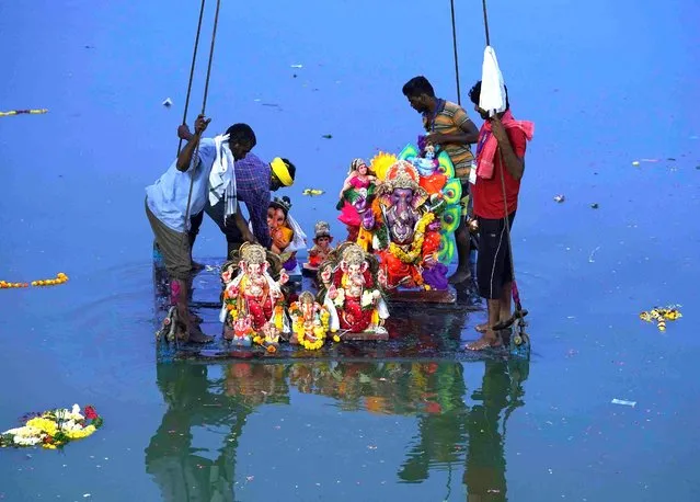Volunteers prepare to immerse Idols of elephant-headed Hindu god Ganesha into the Hussain Sagar Lake in Hyderabad, India, Thursday, September 8, 2022. The festival is a celebration of the birth of Ganesha, the Hindu god of wisdom, prosperity and good fortune. (Photo by Mahesh Kumar A./AP Photo)