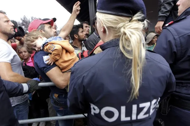 Police officers stand guard as migrants line-up to board trains at the railway station in Nickelsdorf, Austria September 5, 2015. (Photo by Srdjan Zivulovic/Reuters)