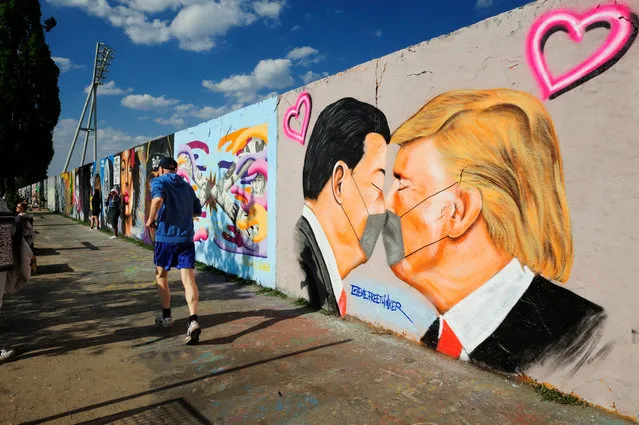 Street art depicts president Trump and president Xi Jinping sharing a kiss in Berlin, Germany on April 27, 2020. (Photo by David Heerde/Rex Features/Shutterstock)