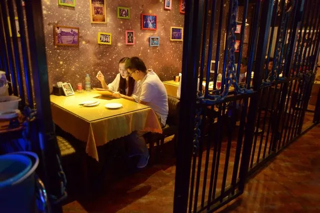 This picture taken on September 9, 2014 shows a couple preparing to have dinner at a prison themed restaurant in Tianjin. (Photo by Wang Zhao/AFP Photo)