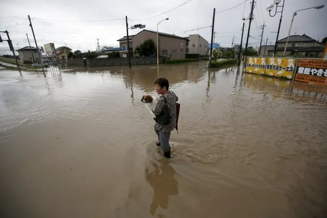 A woman holding her pet dog wades through a residential area flooded by the Kinugawa river, caused by typhoon Etau, in Joso, Ibaraki prefecture, Japan, September 10, 2015. (Photo by Issei Kato/Reuters)