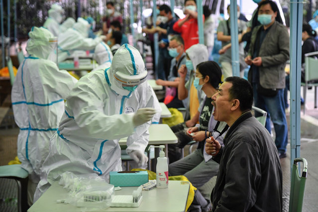 A medical worker takes a swab sample from a resident to be tested for the COVID-19 coronavirus in Wuhan in China's central Hubei province on May 14, 2020. Nervous residents of China's pandemic epicentre of Wuhan queued up across the city to be tested for the coronavirus on May 14 after a new cluster of cases sparked a mass screening campaign. (Photo by AFP Photo/China Stringer Network)