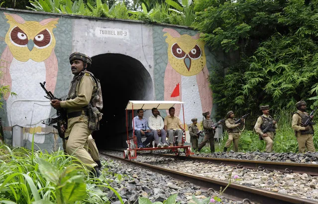 Indian paramilitary force personnel stand alert as railway officials ride on a buggy along tracks through a tunnel in The Baramura Hills, some 43kms north of Agartala on August 11, 2016, during a security search ahead of India's Independence Day celebrations on August 15. (Photo by Arindam Dey/AFP Photo)
