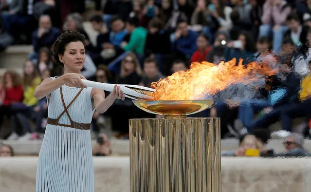 Actress Katerina Lehou playing the role of a high priestess lights an Olympic torch during a handover ceremony for the Olympic Flame at Panathenaic stadium in Athens, on Tuesday, October 31, 2017. The South Korean leg of the relay will involve 7,500 torch- bearers, who will cover a total 2,018 kilometers (about 1260 miles) before the opening ceremony in Pyeongchang, which will host the Feb. 9-25, 2018 Winter Olympics. (Photo by Costas Baltas/Reuters)
