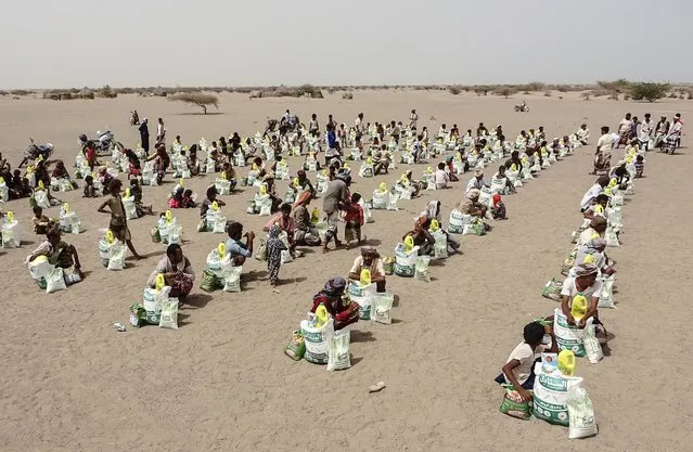 Yemenis displaced by the conflict, receive food aid and supplies to meet their basic needs, at a camp in Hays district in the war-ravaged western province of Hodeida, on July 6, 2022. In Yemen, millions have been forced from their homes in the brutal conflict pitting the Saudi-backed government against Iran-backed Huthi rebels, which has sparked widespread food shortages and ravaged the country's infrastructure. (Photo by Khaled Ziad/AFP Photo)