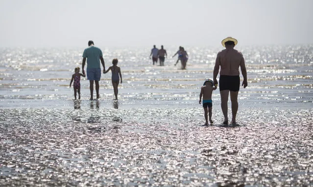 Beachgoers walk towards the sea on Camber Sands on August 25, 2016 in Rye, England.  The day before, five men drowned having got into difficulty when the tides turned in Camber Sands, East Sussex. (Photo by Jack Taylor/Getty Images)