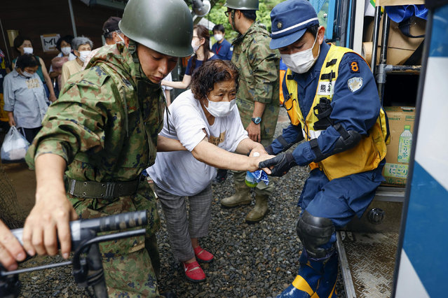 A woman is helped to get into a police vehicle to move from a shelter to another shelter in Kumamura, Kumamoto prefecture, southern Japan Monday, July 6, 2020. Rescue operations continued and rain threatened wider areas of the main island of Kyushu. (Photo by Kota Endo/Kyodo News via AP Photo)