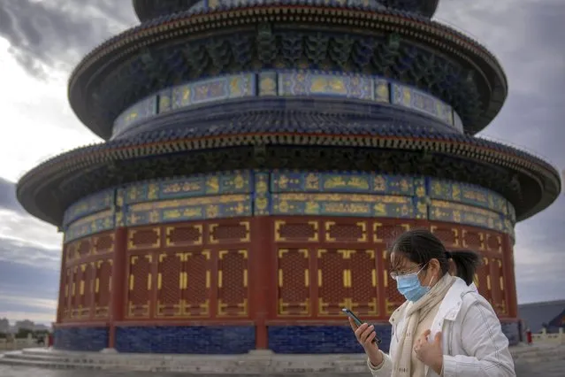 A woman wearing a face mask walks at the Temple of Heaven in Beijing, Saturday, November 12, 2022. (Photo by Mark Schiefelbein/AP Photo)