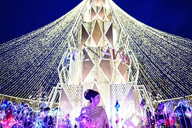 A woman poses for photographs amidst a lights installation during the Bangkok Illumination show at the Iconsiam shopping mall in Bangkok on November 6, 2022. (Photo by Manan Vatsyayana/AFP Photo)
