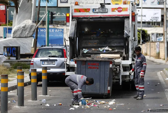 In this Saturday, May 23, 2020 photo, Bangladeshi and Syrian sanitation workers remove garbage from a street, in Beirut, Lebanon. (Photo by Hussein Malla/AP Photo)