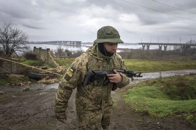 A Ukrainian serviceman patrols area near the Antonovsky Bridge which was destroyed by Russian forces after withdrawing from Kherson, Ukraine, Thursday, December 8, 2022. (Photo by Evgeniy Maloletka/AP Photo)