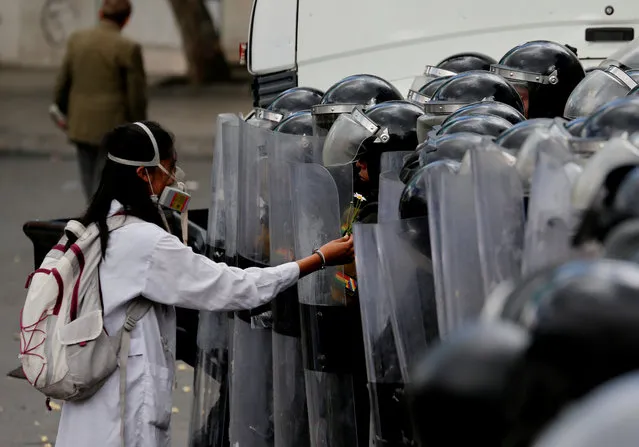 A demonstrator gives a flower to a riot police officer during a rally protest against Bolivia's government new health care policies in La Paz, Bolivia on January 4, 2018. (Photo by David Mercado/Reuters)