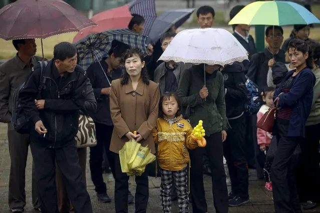 People wait for a bus under the rain in Pyongyang's suburb, October 11, 2015. (Photo by Damir Sagolj/Reuters)