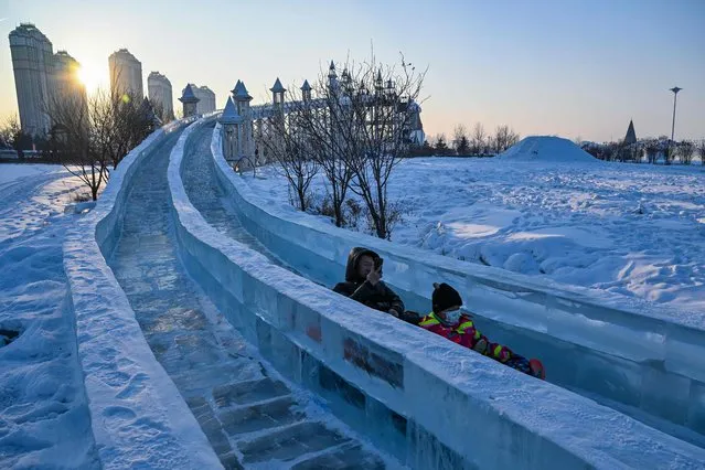 People slide down on a ice slide at an amusement park in Harbin, in China's northeastern Heilongjiang province, on January 4, 2023, ahead of the 39th Harbin China International Ice and Snow Festival. (Photo by Hector Retamal/AFP Photo)