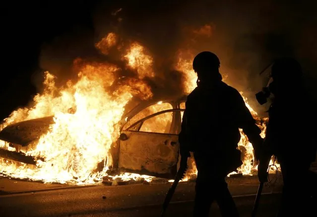 Police walk past a burning police car on the street after a grand jury returned no indictment in the shooting of Michael Brown in Ferguson, Missouri November 24, 2014. (Photo by Jim Young/Reuters)