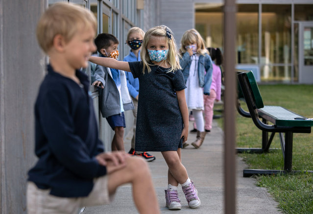 Kindergartner Cameron McManus, 5, watches as a fellow student has his portrait made during “picture day” at Rogers International School on September 23, 2020 in Stamford, Connecticut. Students lined up outside to be photographed while socially distanced due to COVID-19 precautions. Most students at Stamford Public Schools are taking part in a hybrid education model, attending in-school classes every other day and distance learning the rest. (Photo by John Moore/Getty Images)