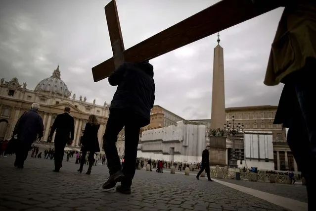 People carry a cross on their way to pray in St. Peter's Square at the Vatican, where Cardinals gathered for their final day of talks before the conclave to elect the next pope, on March 11, 2013. (Photo by Oded Balilty/Associated Press)