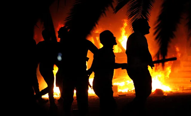 In this Friday, September 21, 2012, file photo, civilians watch fires at an Ansar al-Shariah Brigades compound after hundreds of locals, military, and police raided the Brigades base in Benghazi, Libya. The warring parties in Libya and their international backers — the United Arab Emirates, Russia and Jordan vs Turkey and Qatar — violated a U.N. arms embargo on the oil-rich north African country that remains “totally ineffective”, U.N. experts said in a new report. (Photo by AP Photo/File)