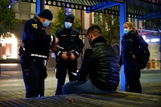 Police officers check the documents of a man as Slovenia starts a nightly curfew from 9 p.m. to 6 a.m as part of a state of emergency called to curb the rising of the coronavirus disease (COVID-19) cases in the country, in Ljubljana, Slovenia, October 20, 2020. (Photo by Borut Zivulovic/Reuters)