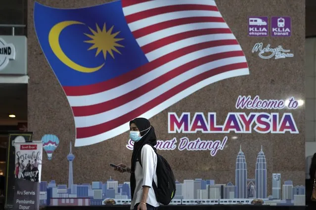 A woman wearing a face mask to help curb the spread of the coronavirus passes through the train station in Kuala Lumpur, Malaysia, Monday, October 12, 2020. Malaysia will restrict movements in its biggest city Kuala Lumpur, neighboring Selangor state and the administrative capital of Putrajaya from Wednesday to curb a sharp rise in coronavirus cases. (Photo by Vincent Thian/AP Photo)