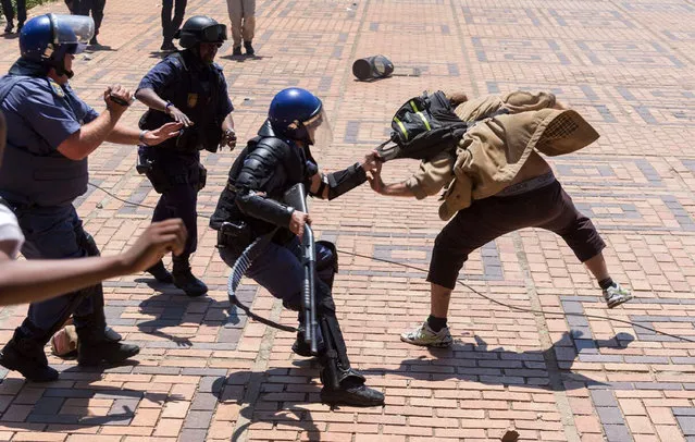 A policeman clashes with a student on the University of the Witwatersrand campus in Johannesburg, South Africa, on Monday, October 10, 2016. Tear gas and water cannon were fired as hundreds of students protested at the university amid a bitter national dispute with university managers and the government over demonstrators' demands for free education. (Photo by Yeshiel Panchia/AP Photo)