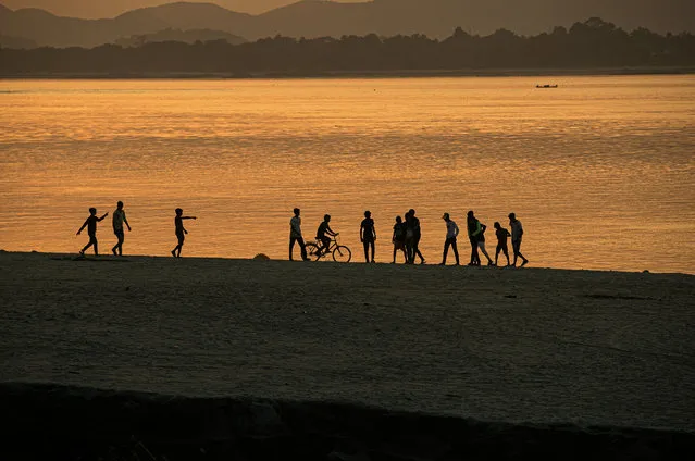 Boys play along the river Brahmaputra as the sun sets in Gauhati, India, Tuesday, November 17, 2020. Brahmaputra is one of Asia's largest rivers, which passes through China's Tibet region, India and Bangladesh before converging into the Bay of Bengal. (Photo by Anupam Nath/AP Photo)