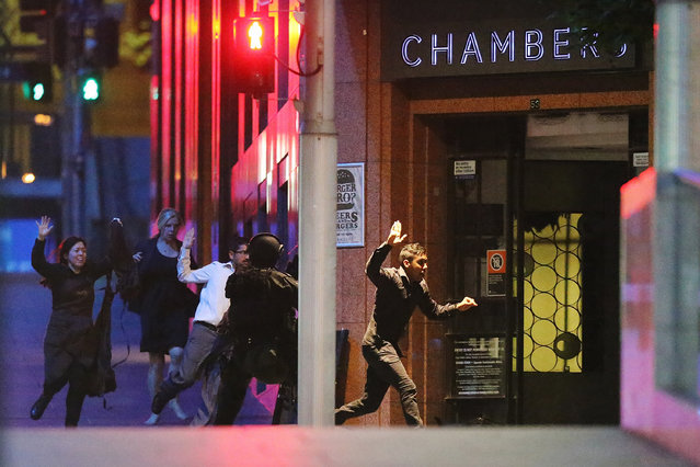 People run with their hands up from the Lindt Cafe, Martin Place during a hostage standoff on December 16, 2014 in Sydney, Australia. Police stormed the Sydney cafe as a gunman has been holding hostages. (Photo by Joosep Martinson/Getty Images)