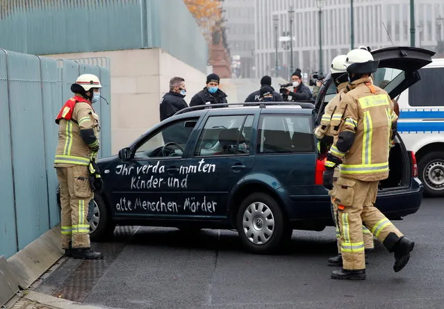 Firefighters remove the car which crashed into the gate of the main entrance of the chancellery in Berlin, the office of German Chancellor Angela Merkel in Berlin, Germany, November 25, 2020. According to a statement, the police are currently clarifying whether the driver hit the gate on purpose. He was taken into police custody. Letters written on the car read: “You damn killers of children and old people”. (Photo by Fabrizio Bensch/Reuters)