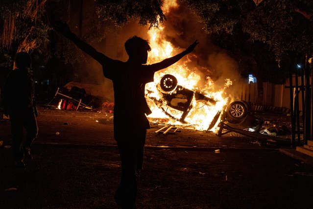 A man walk pass a burning car after being set ablaze during a protest at Yogyakarta Police headquarterson August 29, 2025 in Yogyakarta, Indonesia. Protesters demand economic justice and government accountability as tensions rose in Jakarta and elsewhere following the death of a ride-share driver, who was killed after a police vehicle struck him during demonstrations over living costs and wage reforms. (Photo by Ulet Ifansasti/Getty Images)