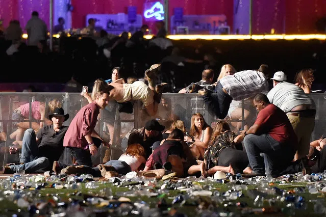 People scramble for shelter after gunshots ring out at the Route 91 country music festival in Las Vegas,  Nev., October 1, 2017. Fifty-eight people were killed and more than 500 wounded when gunman Stephen Paddock opened fire on a crowd of around 22,000 concertgoers at the Route 91 Harvest Country Music Festival at the Mandalay Bay Resort and Casino in Las Vegas, Nev. Paddock fired for ten minutes from a suite on the 32nd floor of the hotel. Paddock killed himself in his hotel room after the shooting. Twenty-three guns were found in his room, some of which had been specially adapted to mimic fully automatic weapons, firing 400 to 800 rounds per minute. Paddock had no criminal record, and no motive was established for the massacre. (Photo by David Becker/Getty Images/World Press Photo)