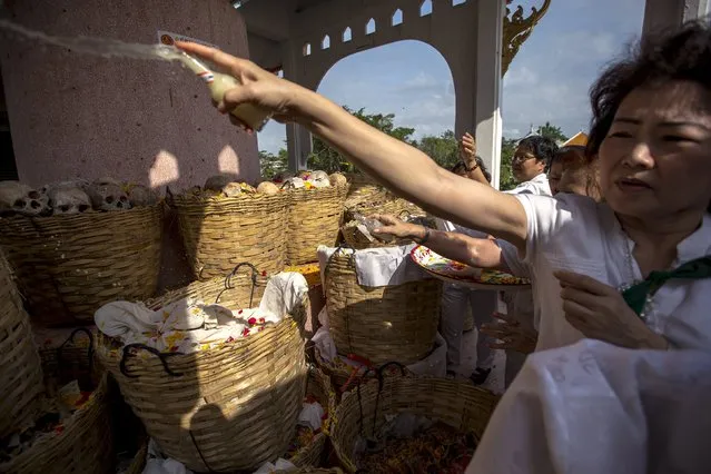 People spray holy water on skulls and skeletons of unclaimed bodies during a buddhist ceremony at the Poh Teck Tung Foundation Cemetery in Samut Sakhon province, Thailand, November 11, 2015. (Photo by Athit Perawongmetha/Reuters)