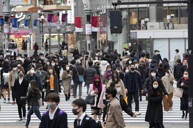 In this December 11, 2020, file photo, people wearing face masks to help curb the spread of the coronavirus walk across an intersection in Tokyo. Tokyo reported 621 new COVID-19 cases Saturday, Dec. 12, setting a new high in the capital of Japan where a lack of government measures has triggered concerns about further upsurge during the holiday season. (Photo by Hiro Komae/AP Photo/File)