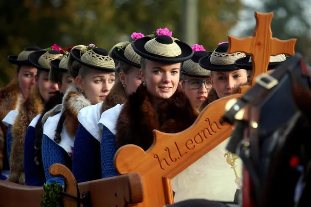 Farmers' wives and children dressed in traditional Bavarian costumes ride in a wooden carriage on the way to the church of Reitham, during the Leonhard procession in Warngau October 23, 2016. The Leonhardi Ritt procession is an annual event that started in the 17th century to pray to St. Leonhard, the patron saint of animals. (Photo by Michael Dalder/Reuters)