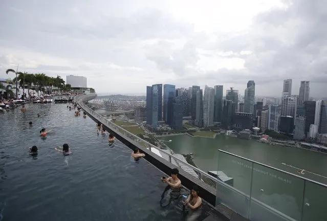 Hotel guests swim in the infinity pool at the Marina Bay Sands hotel overlooking the central business district in Singapore July 16, 2015. (Photo by Edgar Su/Reuters)