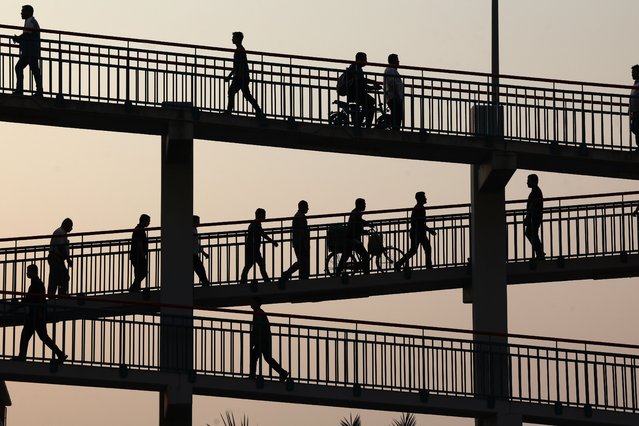 People walk over the E311 at sunset in Dubai after work on October 27, 2025. (Photo by Chris Whiteoak/The National)