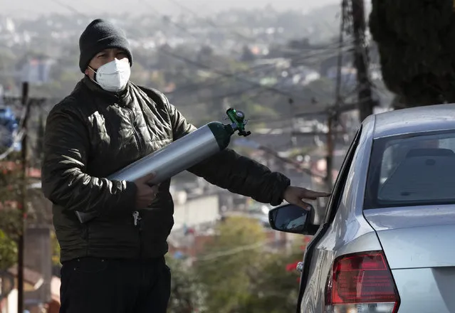 Ricardo Ledesma Carrasco gets into his car after refilling a tank of oxygen at a store for his dad who is being treated for COVID-19 at home in Mexico City, Thursday, December 31, 2020. Carrasco's mother also has COVID-19. (Photo by Marco Ugarte/AP Photo)