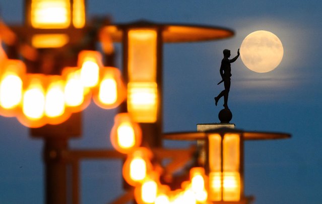 The moon rises on the behind the “Torchbearer” statue in Hannover, Germany, Wednesday, November 5, 2025. (Photo by Julian Stratenschulte/dpa via AP Photo)