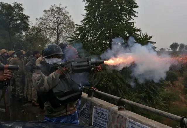 A member of the Rapid Action Force (RAF) fires a tear gas shell towards farmers as they try to cross barricades during a protest against newly passed farm laws on a highway at Dharuhera in the northern state of Haryana, India, January 3, 2021. (Photo by Prashant Waydande/Reuters)