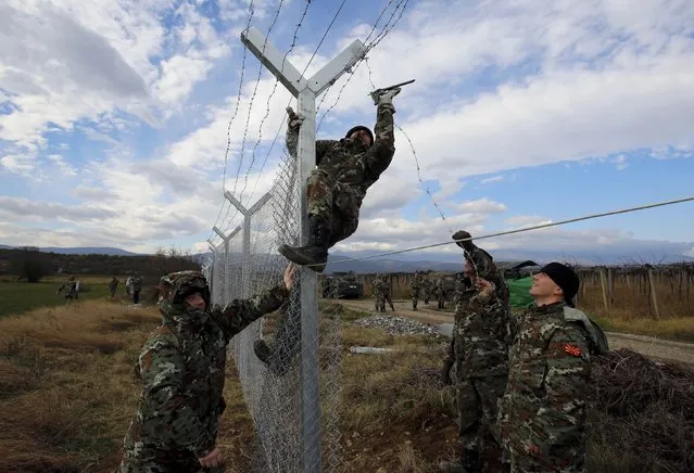 Macedonian soldiers erect a barbed wire fence on the Macedonian-Greek border, near Gevgelija, Macedonia, November 29, 2015. Macedonia, along with other Balkan countries on the migrant route, began turning away "economic migrants" nearly two weeks ago, and earlier on Saturday, began building a barrier similar to that erected by Hungary on its southern border. (Photo by Ognen Teofilovski/Reuters)