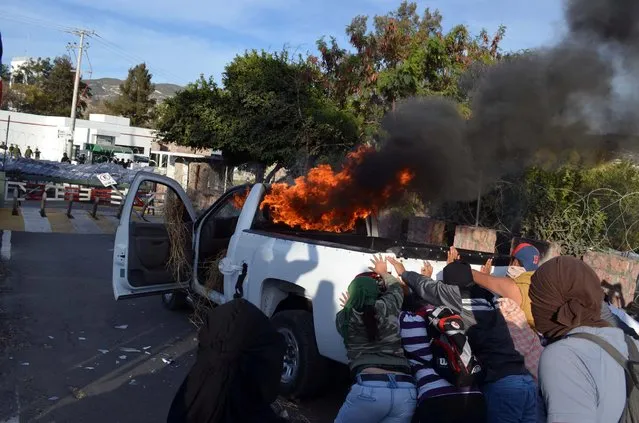 Masked protesters push a burning pick-up truck towards the entrance of an army base in the city of Chilpancingo, Mexico, Monday, January 12, 2015. The protest is part of ongoing unrest after 43 students disappeared on September 26, 2014, allegedly taken by police and handed over to a criminal gang who then killed them, according to government officials investigating the case. (Photo by Alejandrino Gonzalez/AP Photo)