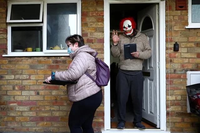 A man waves as volunteers hand out the COVID-19 home test kits to residents, in Goldsworth and St Johns, amid the outbreak of coronavirus disease (COVID-19) in Woking, Britain, February 2, 2021. Volunteers and police officers in several parts of England began knocking on people's doors to hand out COVID-19 testing kits to halt the spread of a highly infectious variant that originated in South Africa. (Photo by Hannah McKay/Reuters)