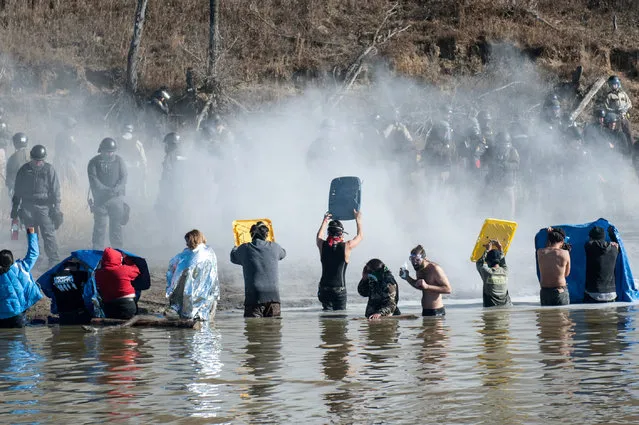 Police use pepper spray against people standing in the water of a river during a protest against the building of a pipeline near the Standing Rock Indian Reservation near Cannonball, North Dakota, U.S. November 2, 2016. (Photo by Stephanie Keith/Reuters)